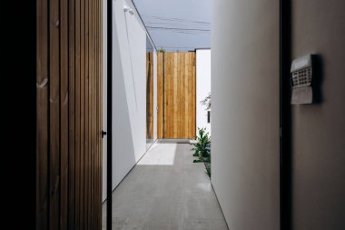 Sağlam ahşap bir kapı ve duvara yapıştırılmış bir posta kutusuyla dolu uzun bir koridor. Hoş geldin atmosferi yaratıyor.