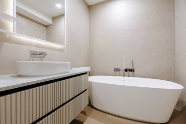 Güzel bir küvet, lavabo ve rahat ve stil için duvar aynası gibi temel özellikleri barındıran iyi tasarlanmış bir banyo.