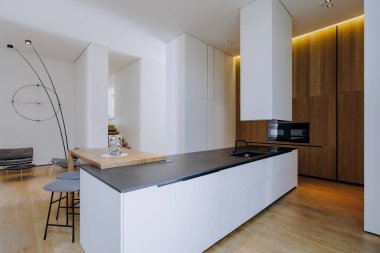 Bu mutfak zarif beyaz dolaplarla çelişen parlak siyah bir tezgaha sahip modern bir estetik yaratıyor.