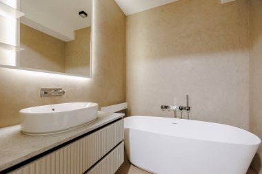 Rahatlatıcı bir küvet, işlevsel bir lavabo ve bakım ve kişisel bakım için şık bir ayna içeren bir banyo.