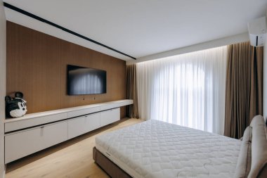 Yatak odasında geniş, rahat bir yatak odası ve eğlence için duvara monte edilmiş düz ekran televizyon var.