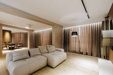 Oturma odasının içinde şık beyaz bir kanepe ve zarif kahverengi perdeler bulunur. Dekor ve ambiyansı mükemmel bir şekilde tamamlar.