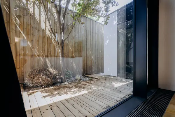 Kırsal ahşap bir güvertenin manzarası camdan görülebiliyor, doğal malzemelerin ve gündüz aydınlatma efektlerinin güzelliğini gösteriyor.