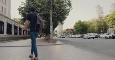 Sırt çantalı yalnız bir adam hareketli bir şehir caddesinde yürüyor, şehir atmosferini özümsüyor ve keşif ve macera ruhunu sergiliyor.