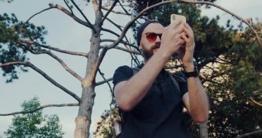 Bir adam dışarıda güzel bir gün geçirmekten zevk alır. Doğanın özünü selfie 'ler ve kamerasıyla görkemli bir ağacın fotoğraflarını çeker.