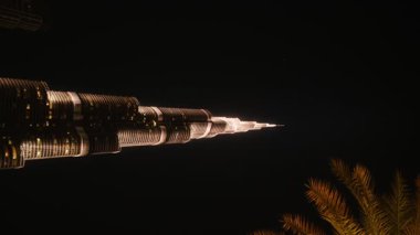 Gecenin en yüksek binasının göz kamaştırıcı aydınlatmasını tecrübe edin. Canlı ışıklar büyüleyici bir şehir manzarası yaratıyor.