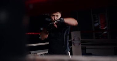 Loş bir boks ringinde, kararlı bir adam yeteneklerini yoğun bir maçta sergiliyor, gölgeler rakibine odaklandıkça dramayı arttırıyor.