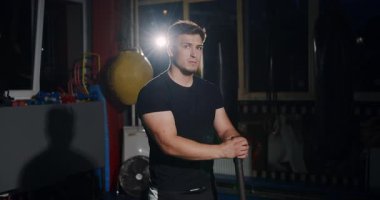 Loş bir boks ringinde, kararlı bir adam yeteneklerini yoğun bir maçta sergiliyor, gölgeler rakibine odaklandıkça dramayı arttırıyor.