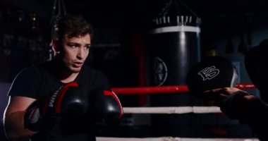 Loş bir boks ringinde, kararlı bir adam yeteneklerini yoğun bir maçta sergiliyor, gölgeler rakibine odaklandıkça dramayı arttırıyor.