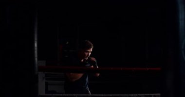 Loş bir boks ringinde, kararlı bir adam yeteneklerini yoğun bir maçta sergiliyor, gölgeler rakibine odaklandıkça dramayı arttırıyor.