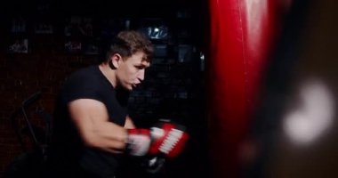 Loş bir boks ringinde, kararlı bir adam yeteneklerini yoğun bir maçta sergiliyor, gölgeler rakibine odaklandıkça dramayı arttırıyor.