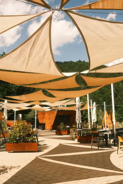 Çok sayıda renkli ve ilginç şemsiye sergileniyor ve meşgul bir restoranın tavanında dekoratif bir şekilde asılı duruyor.