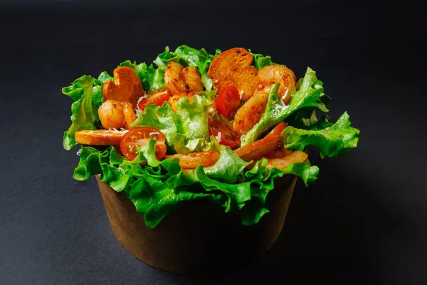 Lezzetli bir salata taze karides, kıtır marul ve olgun domateslerden oluşuyor. Lezzetli bir yemek için kırsal ahşap kasede servis ediliyor.
