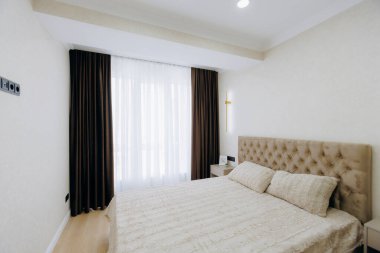 Lüks yatakları, rahat tekstil ürünleri ve sıcak, doğal ışığı davet eden güzel tasarlanmış çağdaş bir yatak odası.