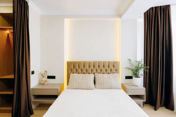 Şık yatak odası tasarımı, sıcak tonlarda, zarif yatak örtüleri ve rahat bir ortam için şık perdeler içerir..