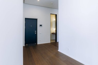 Bu şık giriş, zarif modern bir kapı, güzel ahşap döşeme ve zarif minimalist dekorasyon unsurları sergiliyor.