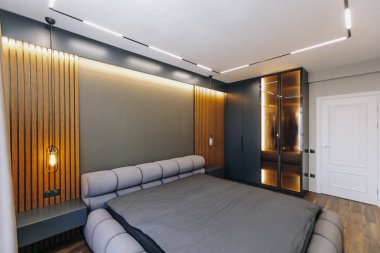 Şık ve modern bir yatak odası tasarımı ortam aydınlatması, şık mobilyalar ve çağdaş dekor unsurları sergiliyor.