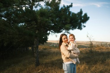 A beautiful and joyful moment captured of a mother lovingly holding her child in a peaceful outdoor setting