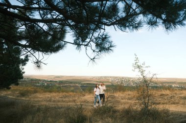 A romantic couple stands close together in a tranquil field surrounded by a stunningly vibrant landscape