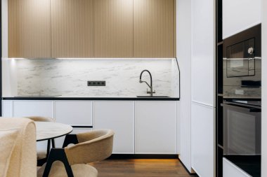 This sleek kitchen showcases a stunning marble backsplash along with stylish minimalist furnishings for a modern look
