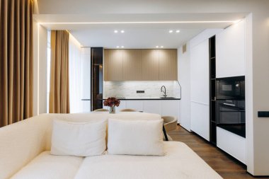 This modern living space has a cozy couch, sleek kitchen, and is designed for contemporary comfort and style