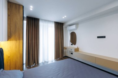 This modern bedroom features stylish curtains, warm inviting lighting, and an overall sleek minimalist design aesthetic