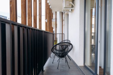 Şık bir balkon, modern sandalyelerin yanı sıra ahşap aksanlı güzel bir açık hava alanı.