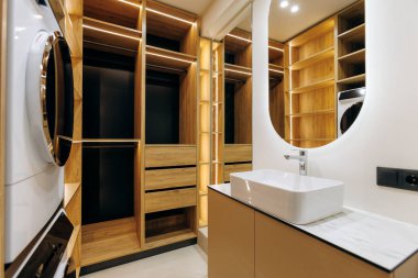 A stylish laundry room showcasing elegant wooden cabinetry, a sleek sink, and highly organized storage solutions