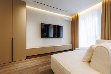 This stylish interior includes a cozy bedroom with modern furniture, a TV, and warm, soothing lighting