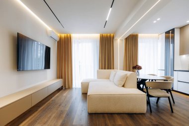 This stylish living room is designed with a sectional sofa, an entertainment TV, and plenty of natural light