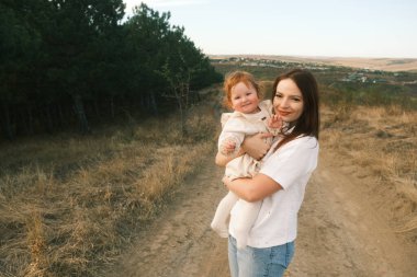 A mother holds her joyful child in a serene landscape, capturing a moment of love and deep connection