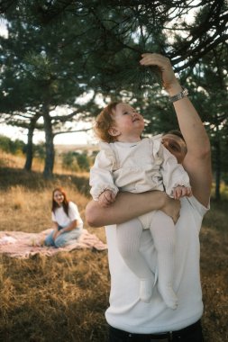 A heartwarming scene depicting a joyful family joyfully enjoying quality time together outdoors amidst towering trees