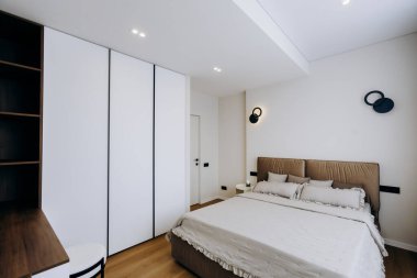 Odanın tam ortasında geniş, geniş bir yatak var. Genel tasarım ve dekorasyon için odak noktası oluşturuyor.