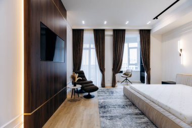 This stylish modern bedroom showcases beautiful dark wood accents, warm soft lighting, and elegant decor throughout