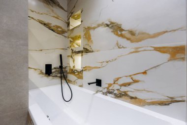Stylish and modern bathroom featuring luxurious marble walls paired with a sleek and elegant bathtub design