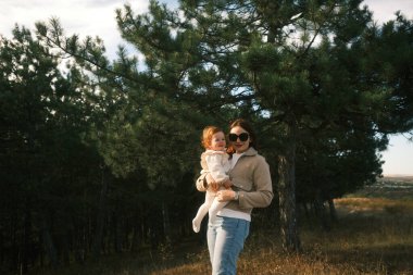 A truly heartwarming moment of a loving mother holding her precious child, surrounded by beautiful trees