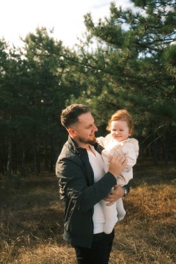 A joyful father lifts his daughter in a scenic forest setting, capturing a moment of love and happiness.