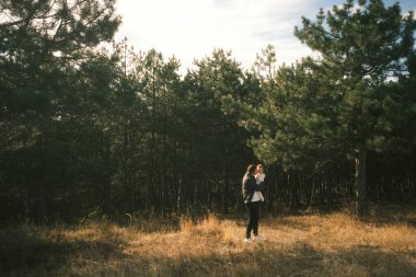 A tranquil moment of an individual sitting quietly in a lush forest clearing, enjoying warm natural light