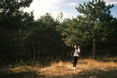 A young individual is savoring a serene and peaceful moment in the heart of a sundrenched forest environment
