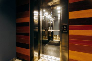 The stylish interior of the elevator features a combination of sleek metallic surfaces and warm wooden design elements