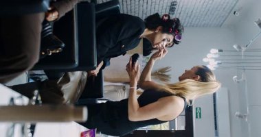 In a stylish salon environment, a skilled stylist is applying makeup on a client who has hair rollers in her hair