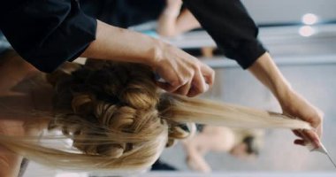 A hair stylist expertly creates an intricate updo, showcasing modern techniques in a professional setting.