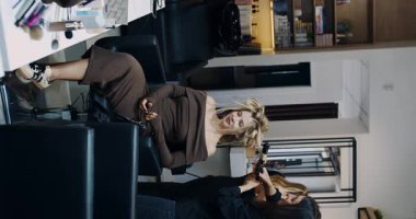 A chic and stylish woman takes pleasure in hairstyling, beautifully showcasing her creativity within a modern studio