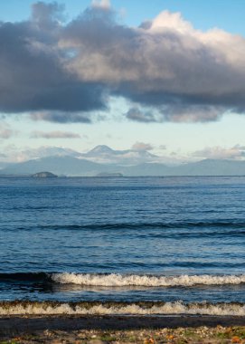 Gündoğumunda Taupo Gölü manzarası ve Yeni Zelanda 'da arka planda dağlar