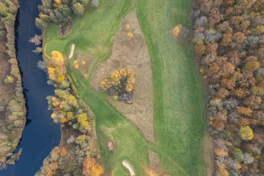 Sonbaharda çok renkli ağaçların havadan görünüşü, ve yeşil çimenler, orman, vahşi doğa, nehir, zıtlıklar. Köyde güzel bir sonbahar. Golf sahası. 