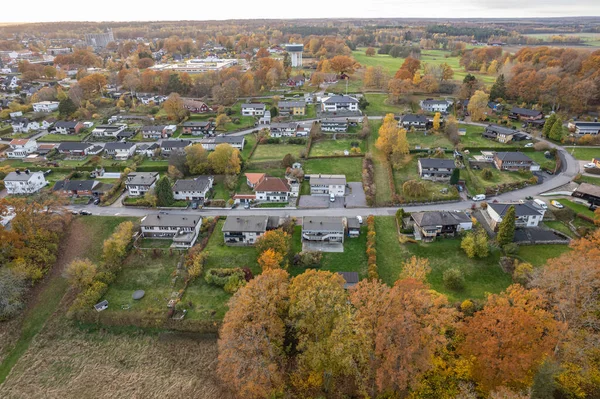 Aerial view on a little village in Europe, private houses. Multicolored trees in autumn, and green grass, forest, wild nature, river, contrasts. Cozy atmosphere.