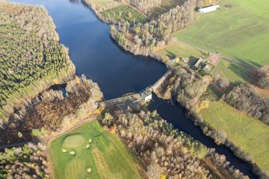 Küçük bir köydeki barajın hava manzarası. Nehir, sonbahar doğası, orman.