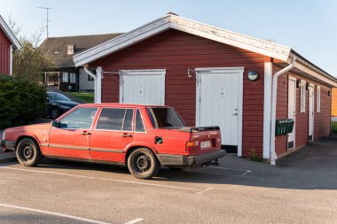 İsveç, Knislinge 24 Nisan 2022: Geleneksel kırmızı İsveç ahşap evinin önünde eski kırmızı bir Volvo araba