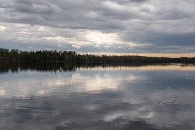 Baharda güzel bir göl, dinamik gri gökyüzü, bulutlar. Sudaki yansıma. Dinlenmek için yer.