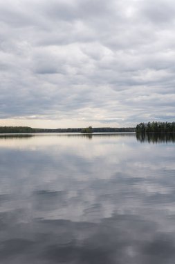 Baharda güzel bir göl, dinamik gri gökyüzü, bulutlar. Sudaki yansıma. Dinlenmek için yer.